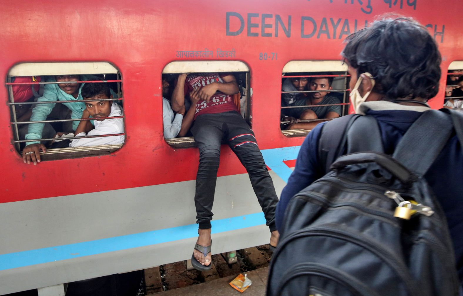 A migrant worker attempts to board an overcrowded train in Mumbai.