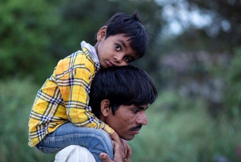 A migrant worker carries a child as they walk along a road in New Delhi.