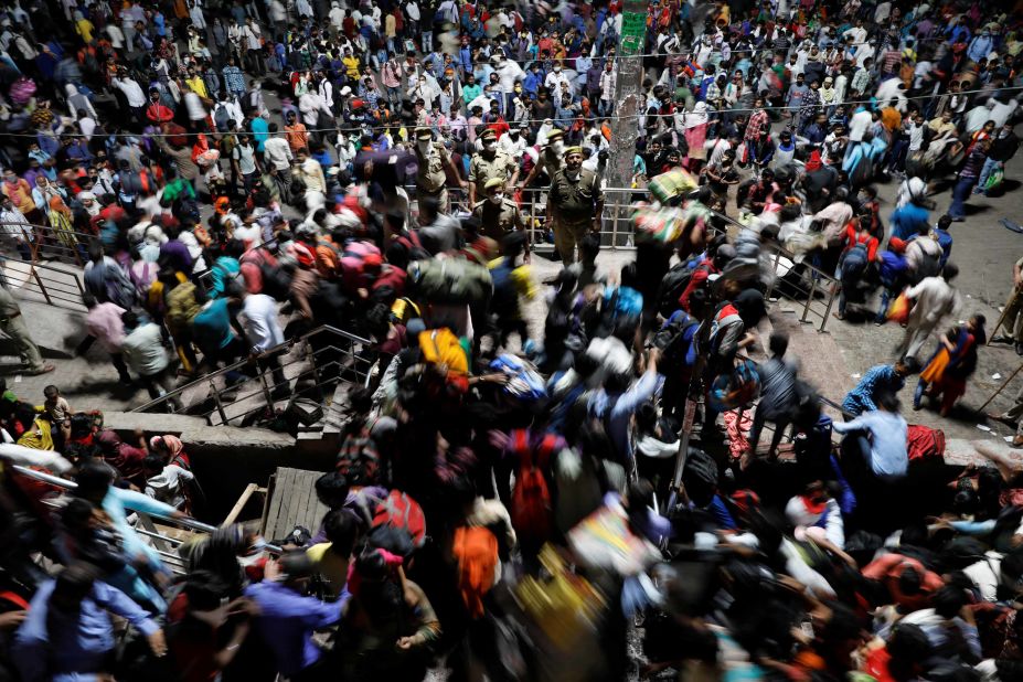 Police officers stand by as migrant workers scramble inside a bus station in Ghaziabad, India, on Saturday, March 28.