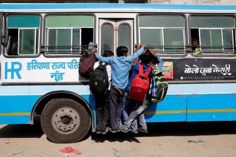 People hang on to a door of a moving bus on the outskirts of New Delhi.