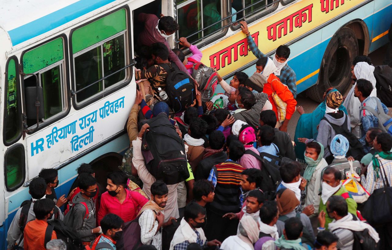 Migrant workers try to board a crowded bus in Ghaziabad on Sunday, March 29. The state governments of Uttar Pradesh, Bihar and Haryana arranged for hundreds of buses to ferry migrants home, causing chaotic scenes as thousands descended upon stations trying to claw their way onto buses.