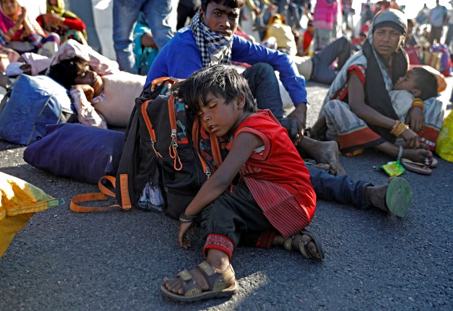 The child of a migrant worker sleeps alongside a highway after the family failed to catch a bus.