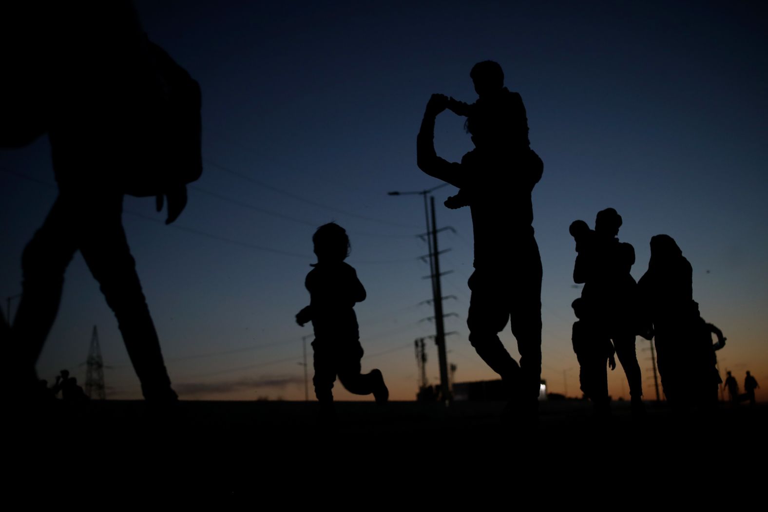 A laborer's family is silhouetted in New Delhi as they journey to their village by foot.