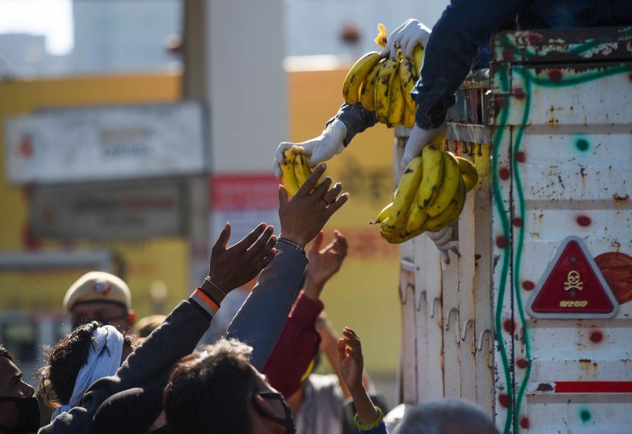 Workers collect food being handed out near the Anand Vihar Bus Terminus in New Delhi.