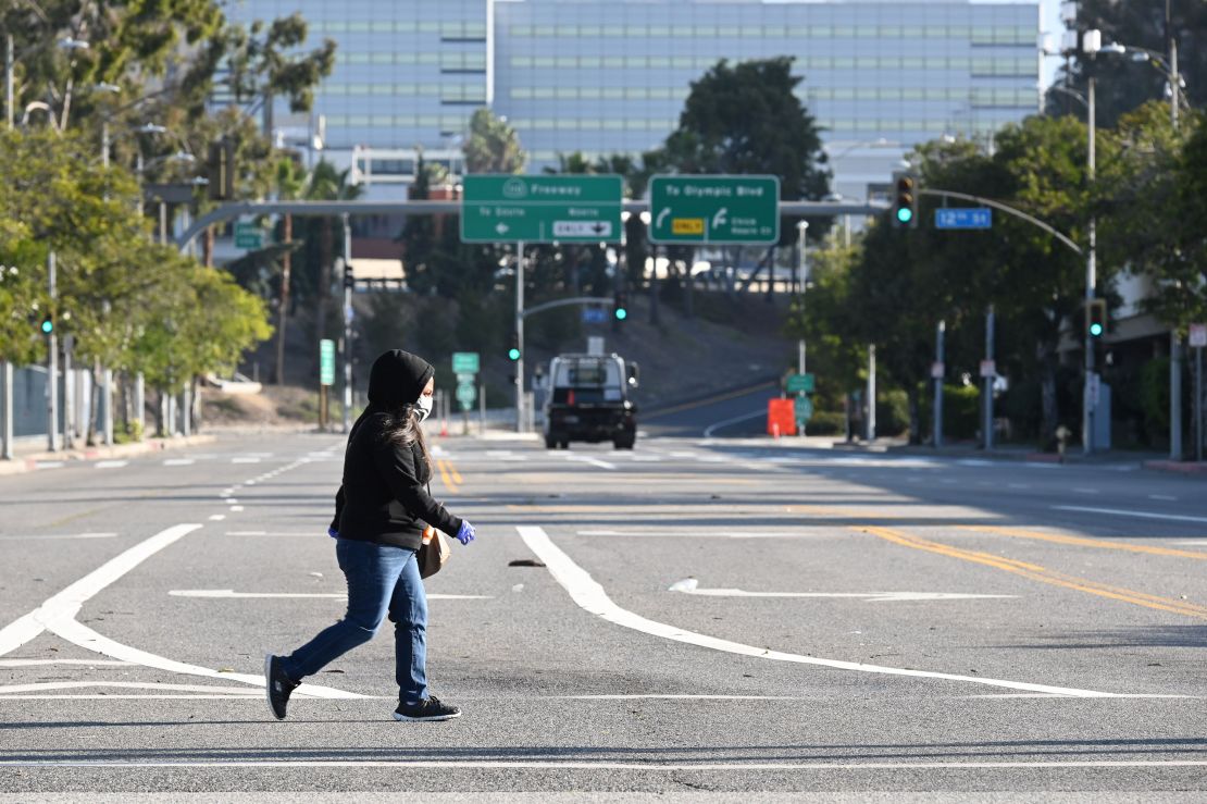 A woman wears a mask as she crosses an empty street near the Los Angeles Convention Center.