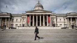  A man wearing a protective face-mask walks through a deserted Trafalgar Square on March 30, 2020 in London, England. 