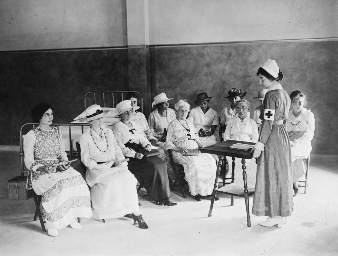An unidentified Red Cross nurse teaches a class on home hygiene and care for the sick to a group of women of various ages, 1920.