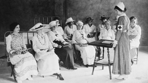 An unidentified Red Cross nurse teaches a class on home hygiene and care for the sick to a group of women of various ages, 1920.
