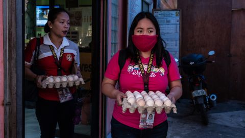 Rosalie Natividad wears a makeshift mask as she carries eggs to local families.