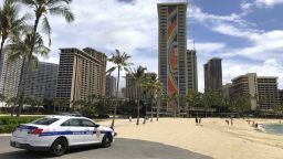 A police officer arrives to tell people to leave Waikiki Beach in Honolulu on Saturday, March 28, 2020. Like many cities across the world, Honolulu came to an eerie standstill this weekend as the coronavirus pandemic spread throughout the islands. But Hawaii officials went beyond the standard stay-at-home orders and effectively flipped the switch on the state's tourism-fueled economic engine in a bid to slow the spread of the virus. As of Thursday, anyone arriving in Hawaii must undergo a mandatory 14-day self-quarantine. The unprecedented move dramatically reduced the number of people on beaches, in city parks and on country roads where many people rely on tourism to pay for the high cost of living in Hawaii. (AP Photo/Caleb Jones)