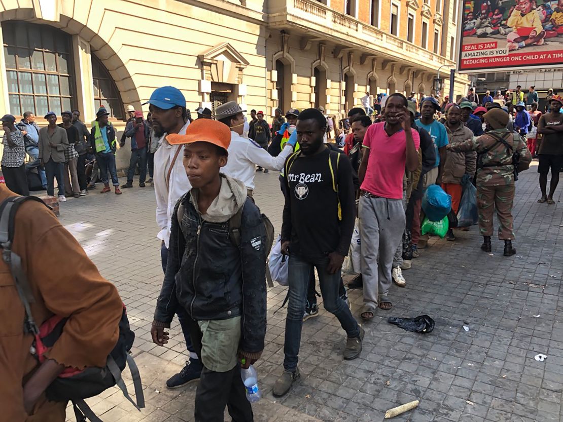 Lines of homeless South Africans await police transport to temporary shelters in downtown Johannesburg.