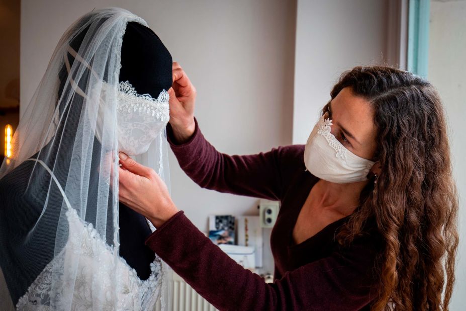 Designer Friederike Jorzig adjusts a mannequin wearing a wedding dress and a face mask at her store in Berlin on March 31, 2020.