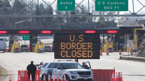 US Customs officers stand beside a sign at the US-Canada border in Lansdowne, Ontario, on March 22, 2020. 