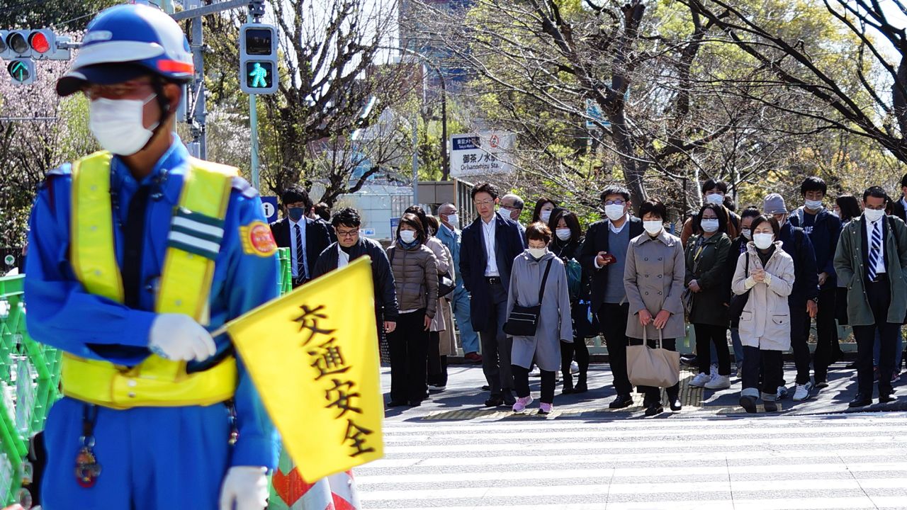People wearing a protective face mask wait at a pedestrian crossing Thursday, April 2, 2020, in Tokyo. 