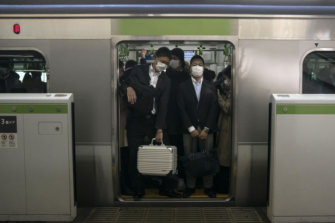 Commuters wearing face masks ride on a train on March 26, 2020 in Tokyo, Japan. 