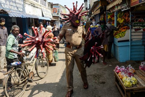 A police officer wearing a coronavirus-themed outfit walks in a market in Chennai, India, to raise awareness about social distancing.