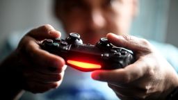 02 April 2020, Berlin: A young man plays in front of the television with the Playstation game console. To prevent infection with the corona virus, many people spend their free time at home. (Photo by Britta Pedersen/picture alliance via Getty Images)