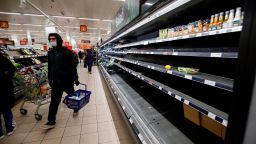 People shop in aisles with empty shelves in a Sainsbury's supermarket in Walthamstow, east London on March 20, 2020. - The British prime minister urged people in his daily press conference on March 19 to be reasonable in their shopping as supermarkets emptied out of crucial items -- notably toilet roll -- across Britain. The government said it was temporarily relaxing elements of competition law to allow supermarkets to work together to maintain supplies. (Photo by Tolga Akmen/AFP/Getty Images)