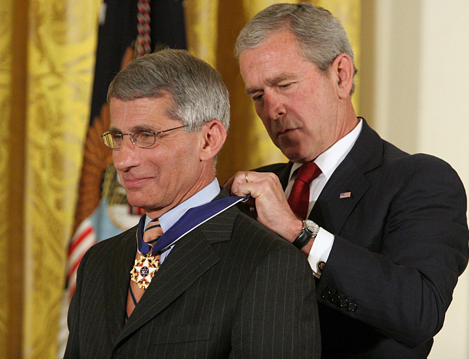 In 2008, US President George W. Bush presents the Presidential Medal of Freedom to Fauci "for his determined and aggressive efforts to help others live longer and healthier lives."