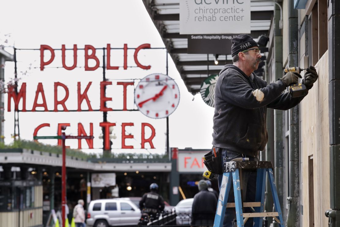 A carpenter covers a closed store with plywood panels near the Pike Place Market in downtown Seattle amid the stay-at-home order.