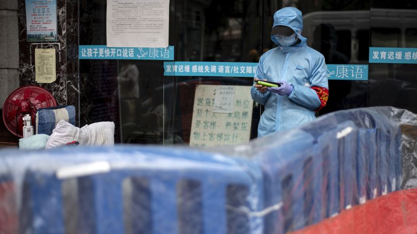 A community volunteer uses her mobile phone near a barrier separating a residential compound in Wuhan, China's central Hubei province on April 2, 2020. - Wuhan, the epicentre of the coronavirus pandemic, is very slowly re-emerging from more than two months of demoralising lockdown. But endless rows of plastic yellow or blue barriers now run along streets throughout the city of 11 million people, just one indication of how life for its traumatised residents remains severely disrupted. (Photo by NOEL CELIS / AFP) (Photo by NOEL CELIS/AFP via Getty Images)