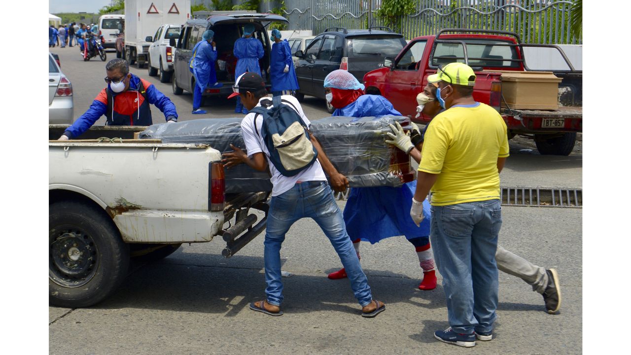 Men with protective suits load a coffin into a car in front of a Guayaquil hospital.