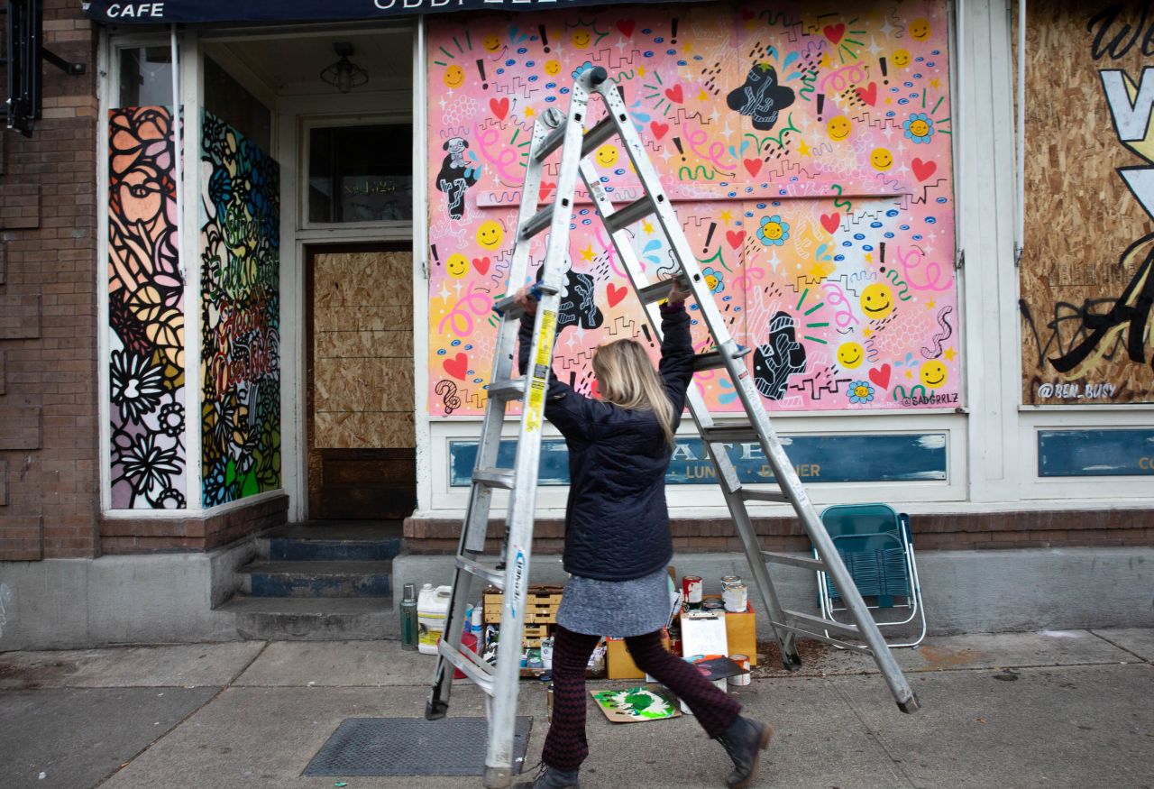 Artist Josephine Rice paints a mural in a boarded-up doorway in Seattle on March 24.