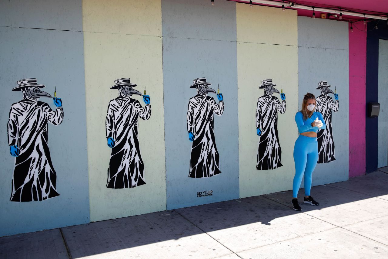A woman has her picture taken by her friends at a boarded-up business in Las Vegas on March 25. Local artists have been painting the boards on shuttered businesses in the Arts District.