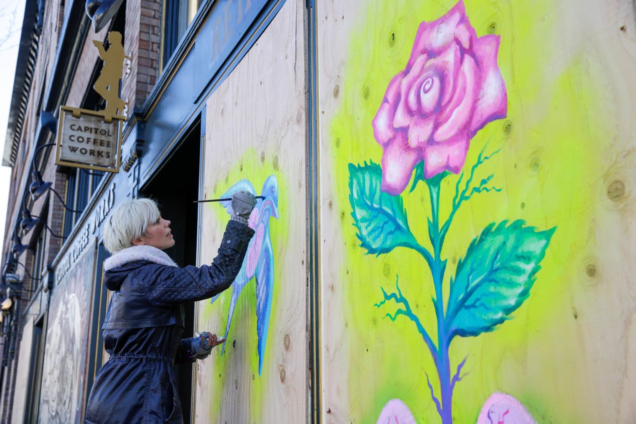 Artist Burgandy Viscosi works on a piece she calls "Healthy Lungs" on a boarded-up coffee shop in Seattle on March 29.
