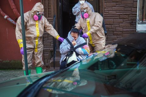 A woman suspected of having coronavirus is helped from her home by emergency medical technicians Robert Sabia, left, and Mike Pareja, in Paterson, New Jersey.