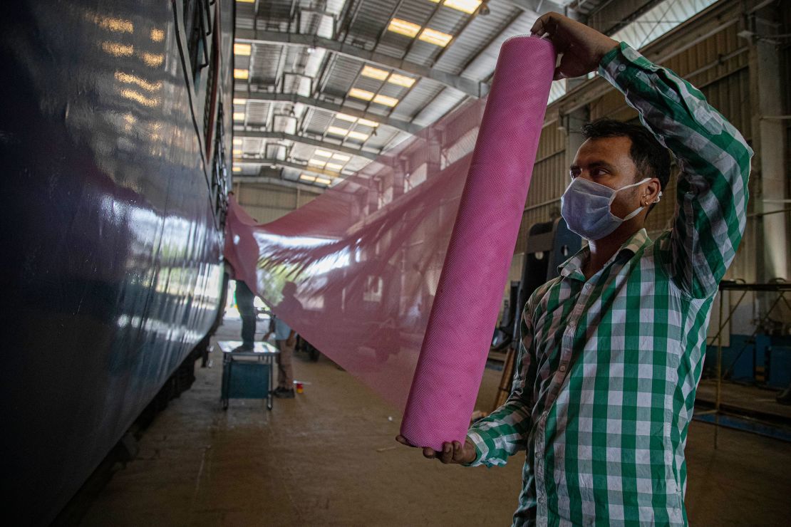 Indian railway employees fix mosquito nets as they work to convert a train coach into an isolation ward for the fight against the new coronavirus in Gauhati, India, Sunday, March 29, 2020.  