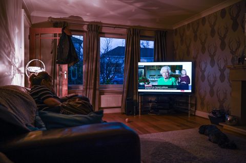 A woman in Glasgow, Scotland, watches Britain's Queen Elizabeth II give a television address regarding the coronavirus pandemic.