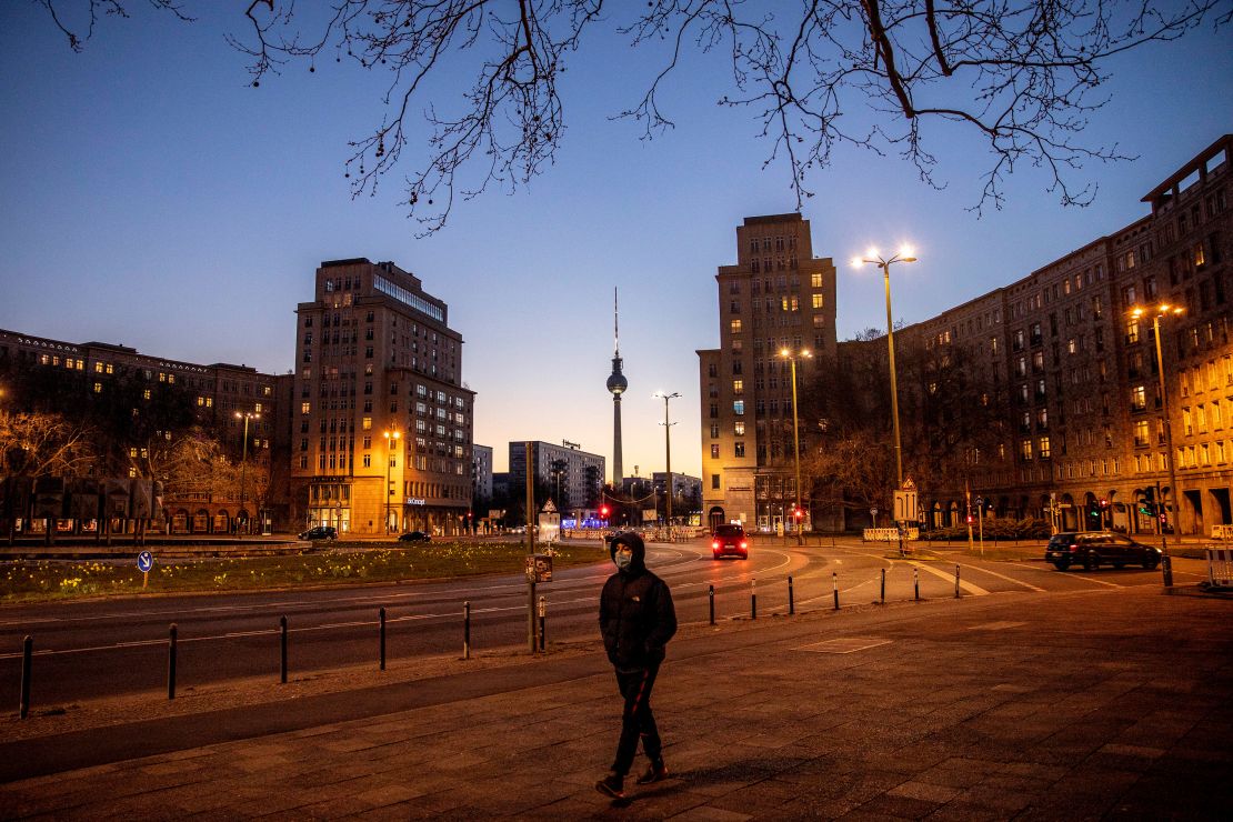 A man with a mask passes by an empty street during the coronavirus crisis in Berlin, Germany.