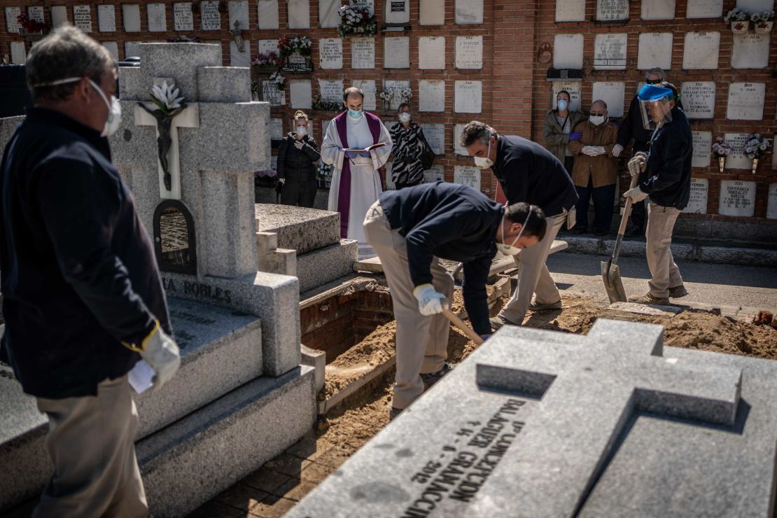 A priest and relatives pray as a victim is buried at the cemetery on March 28.