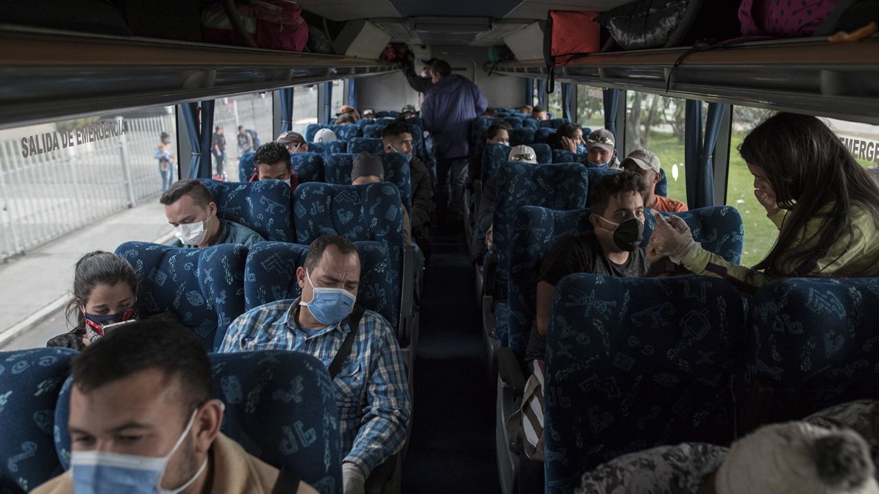 Venezuelan migrants wear protective masks while sitting on a bus that will return them back to Venezuela, in Bogota, Colombia, on Sunday, April 5, 2020.