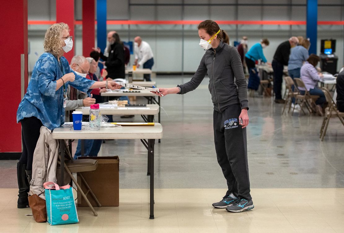 Bridget McDonald, right, receives a ballot from poll worker Patty Piek-Groth on April 7, 2020, at the Janesville Mall in Janesville, Wisonsin. 