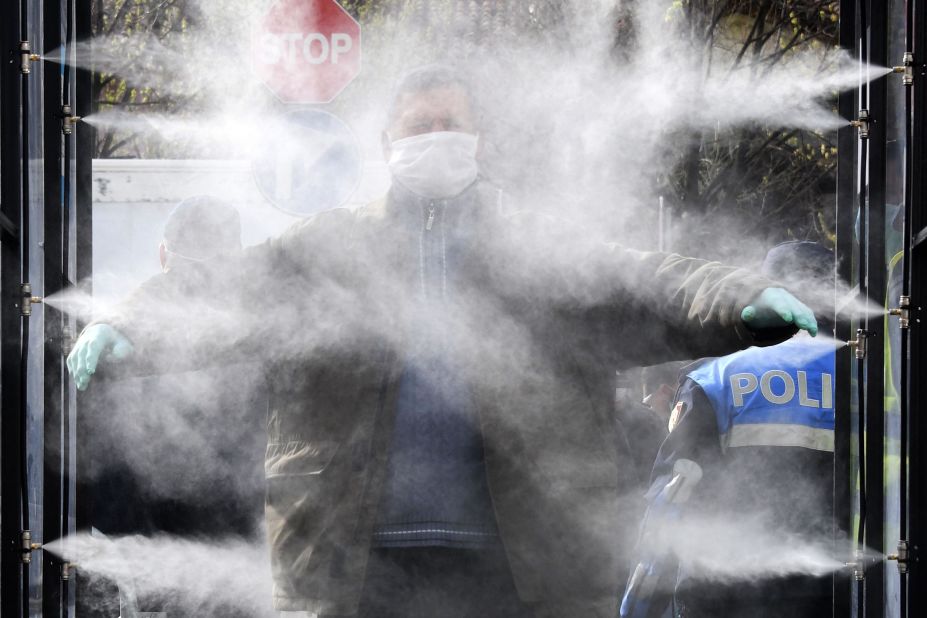 A man is sprayed with disinfectant prior to going to a market in Tirana, Albania.