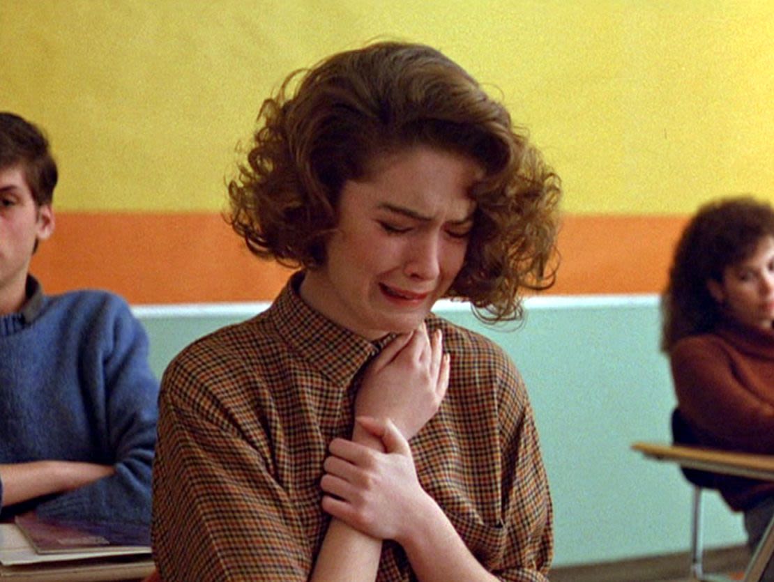 Lara Flynn Boyle como Donna Hayward llorando en su escritorio