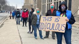 Jennifer Taff holds her homemade sign as she waits in line to vote at Washington High School in Milwaukee on April 7, 2020. 