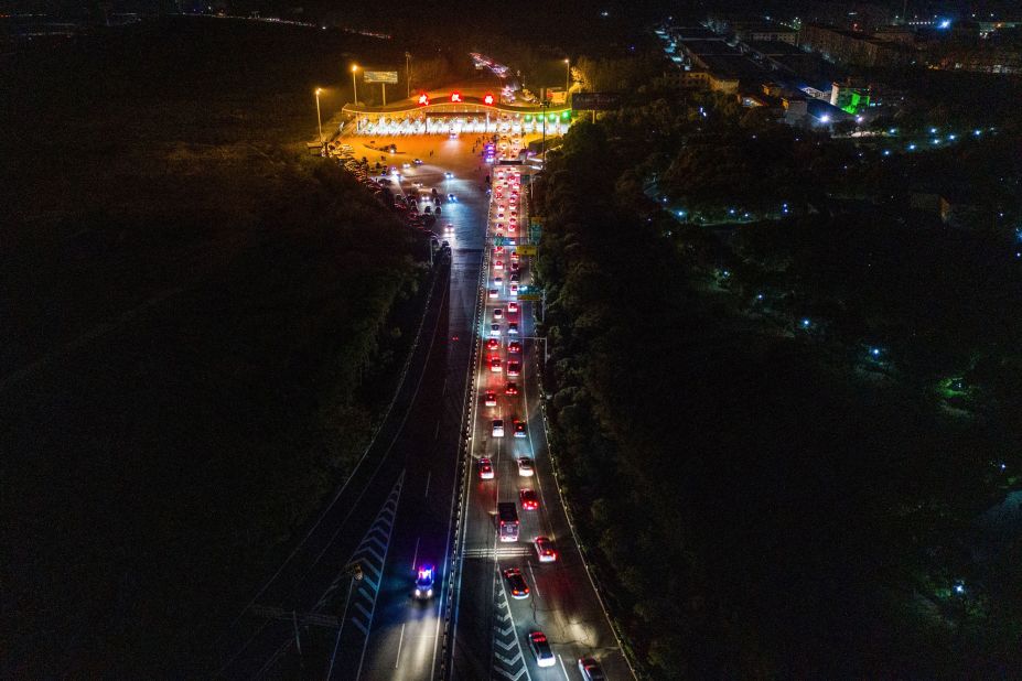 Cars in Wuhan line up to leave at a highway toll station.
