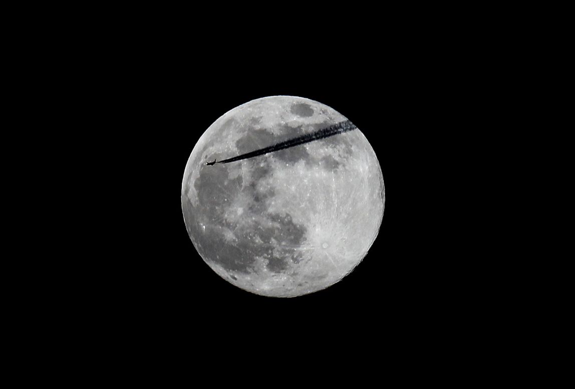 A plane passes the pink supermoon as it rises over Dublin, Ireland. 