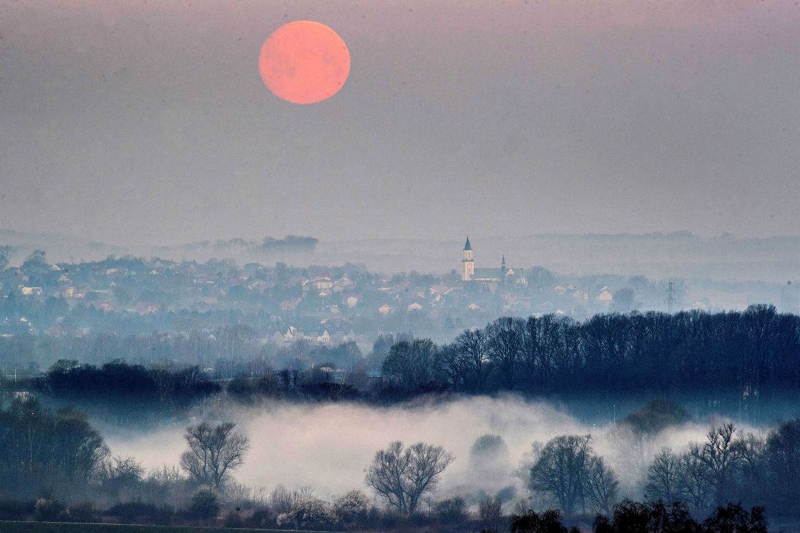 The moon takes on a reddish hue as it reflects the light of early dawn in Krakow, southern Poland.
