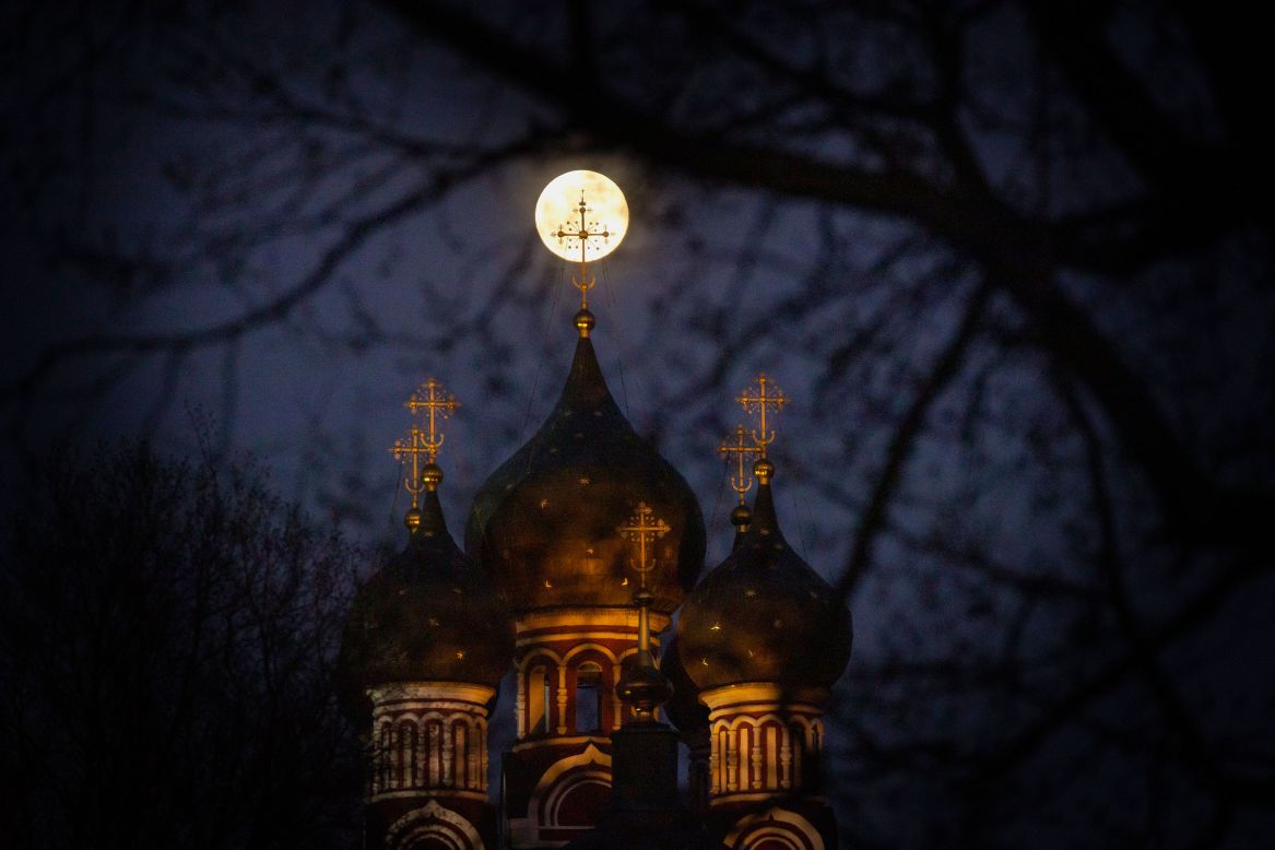 The supermoon rises behind an illuminated cross from an Orthodox church in Moscow.