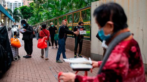 Chu Kin Lik, 61, makes sure people keep their distance as they wait for dinner at Impact HK's meal service on Tuesday, April 7