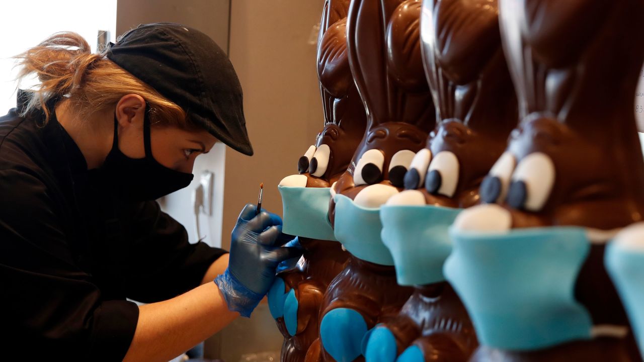 An employee of cake shop prepares chocolate Easter bunnies with masks in Greece.