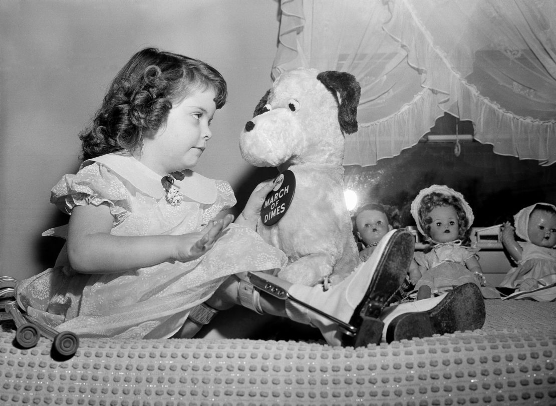 Marlene Olsen, 4, who was named March of Dimes poster girl for 1957, pins a polio drive badge on her stuffed dog, at her home in Burlington, Massachusetts, in 1956. 