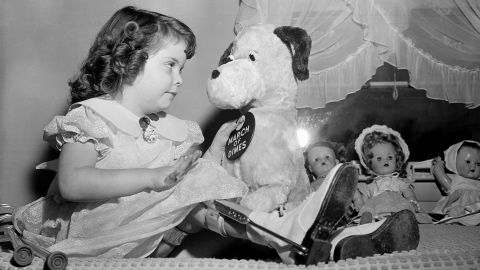 Marlene Olsen, 4, who was named March of Dimes poster girl for 1957, pins a polio drive badge on her stuffed dog, at her home in Burlington, Massachusetts, in 1956. 
