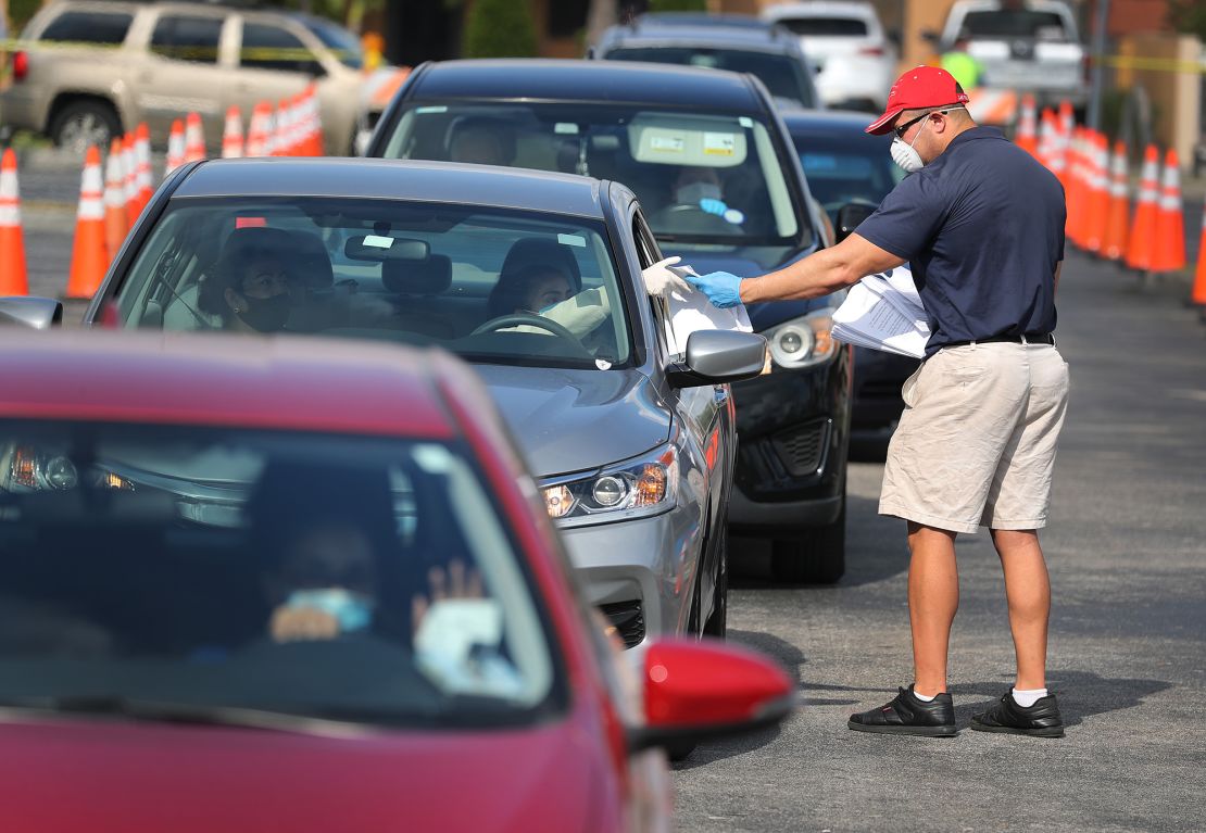 Miguel Diaz, who works for the Florida city of Hialeah, hands out unemployment applications to people in their vehicles in front of a library Wednesday.