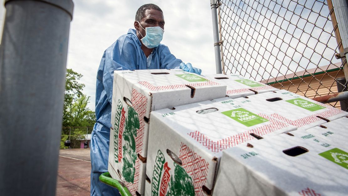 A worker wearing a protective mask and gloves moves boxes of produce to a refrigerated trailer in Jackson, Mississippi.