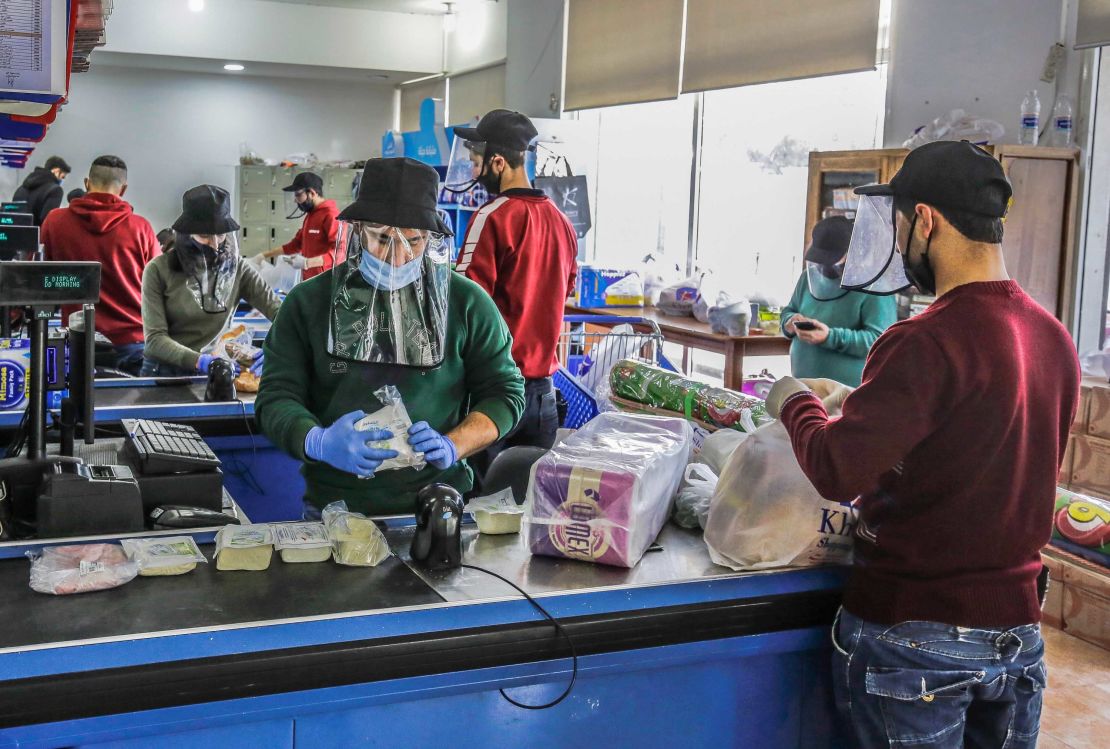 Employees work while wearing protective face shields and gloves at a store in the northern Lebanese city of Batroun on March 23.